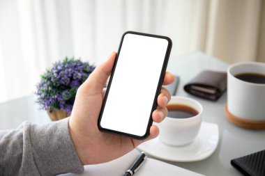 Ofisteki bir masanın üzerinde yalnız ekranlı telefonu tutan erkek eller.