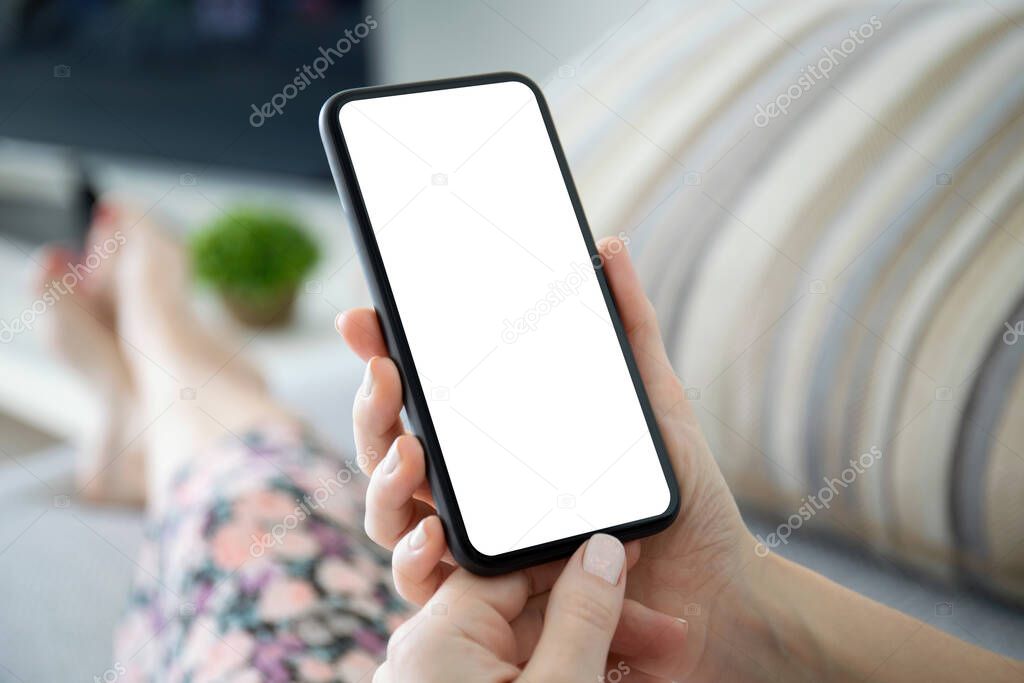 female hands holding phone with isolated screen in the room on the sofa