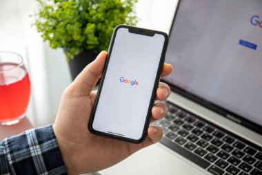 Anapa, Rusya - 22 Şubat 2020: Man hand holding iPhone 11 on Macbook Pro 16 üzerinde sosyal ağ hizmeti Google ekranda. Macbook Pro 16 ve iPhone 11 Apple Inc..