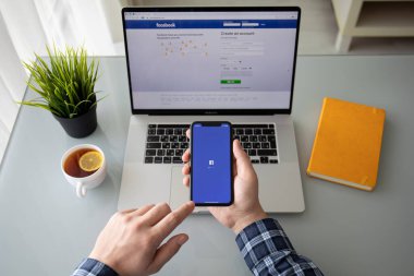 Anapa, Rusya - 22 Şubat 2020: Masada Macbook Pro 16 ve iPhone 11 'de insan eli ile sosyal ağ hizmetleri Facebook ekranında. Macbook ve iPhone Apple tarafından yaratıldı ve geliştirildi.