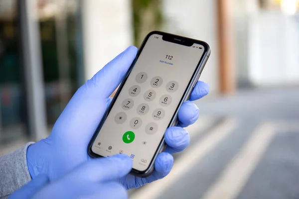 土耳其阿拉亚 2020年3月24日 男子手拿着印有电话号码Sos的Iphone 11的一次性防护手套 — 图库照片