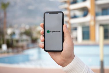 Alanya, Türkiye - 31 Mart 2020: Ekranda sosyal ağ hizmeti TripDanışmanı ile iPhone 11 'i tutan adam. iPhone Apple tarafından oluşturuldu ve geliştirildi..