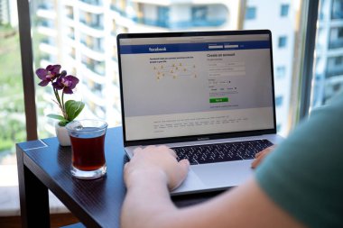 Alanya, Türkiye - 10 Nisan 2020: Ekranda sosyal ağ hizmetleri Facebook 'u olan Macbook Pro 16' ya erkek eli uzattı. Macbook Apple tarafından yaratıldı ve geliştirildi..