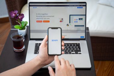Alanya, Türkiye - 10 Nisan 2020: Erkek eli Macbook Pro 16 ve iPhone 11 'de Zoom Video İletişim uygulamasını arıyor