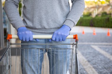 Coronavirus virüsü eldiveni giymiş bir adam yiyecek vagonunu depoda tutuyor.
