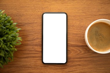 Ofisteki kahve fincanının üzerinde izole ekran olan telefon.