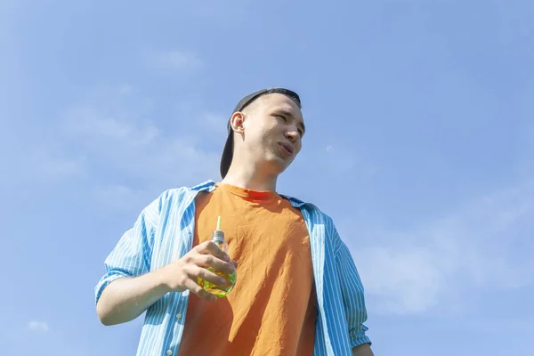 A guy with a beverage in his hand against a blue sky — Stock Photo, Image