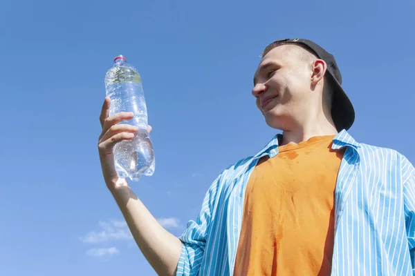 Kerel met een waterfles tegen de lucht — Stockfoto