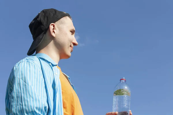 Kerel met een waterfles tegen de lucht — Stockfoto