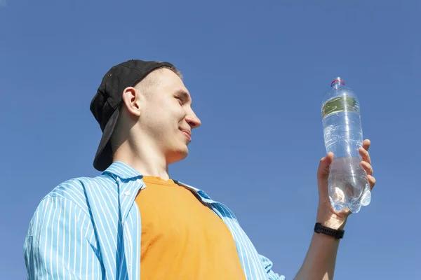 Guy with a water bottle against the sky — Stock Photo, Image