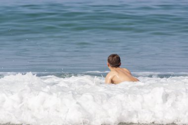 Deniz köpüğünde oturan bir çocuk