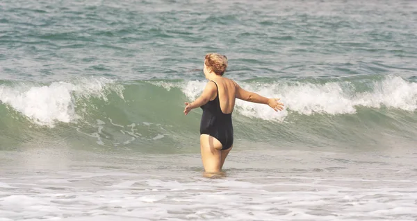 Жінка стоїть перед хвилею з простягнутими руками — стокове фото