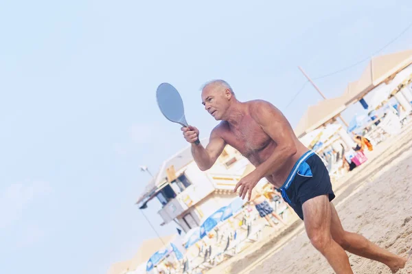 Adulto macho jugando matkot en la playa — Foto de Stock