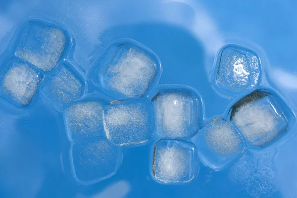 Cubetti di ghiaccio sciolto su uno sfondo blu — Foto Stock