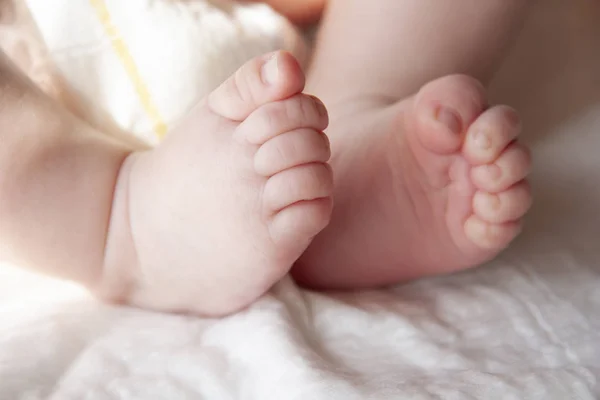 Les jambes du bébé avec de petits doigts roses — Photo