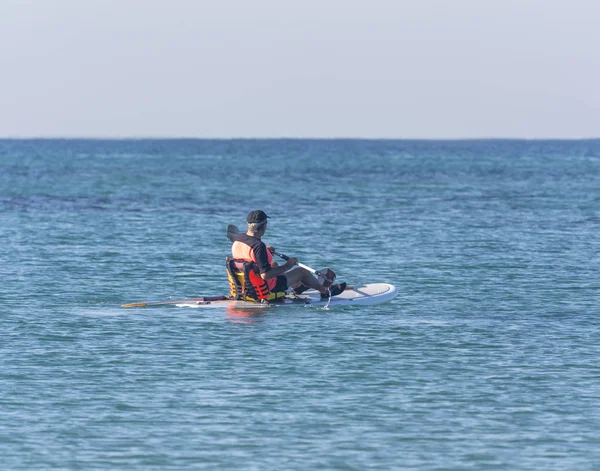 Uomo anziano attivo remare su una tavola da surf — Foto Stock