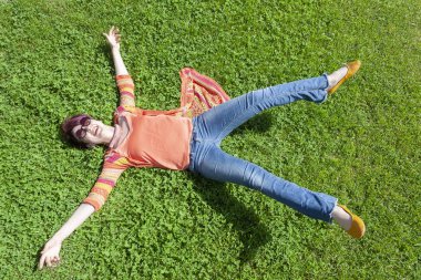 Neşeli kız kollarını açmış çimlere düşüyor.