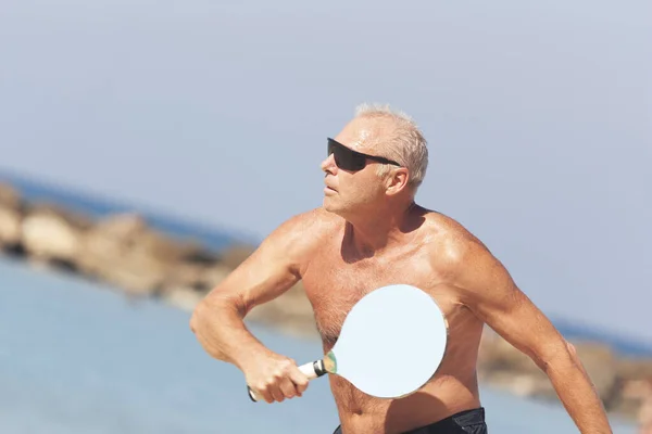 Adulto macho jugando matkot en la playa — Foto de Stock