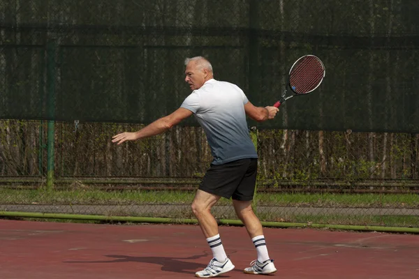 Muž hraje tenis na venkovním hřišti — Stock fotografie