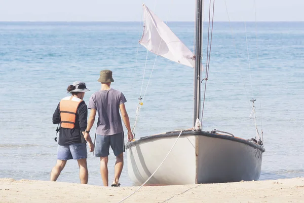 Gli uomini vanno alla barca ormeggiata sulla riva — Foto Stock