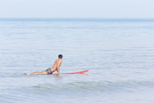 Handsome guy lying on surfboard on water — 스톡 사진