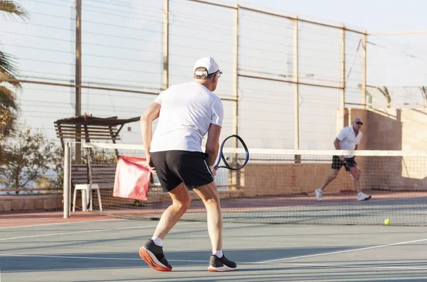 Older men play tennis on an outdoor court — Stock Photo, Image