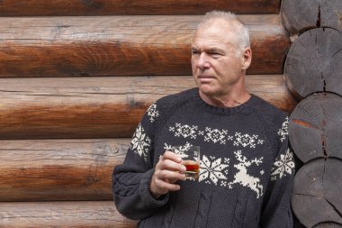 Elinde bir bardak viski olan bir adam.