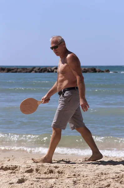 handsome grown man playing tennis on the beach