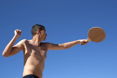 Adam sahilde matkot oynuyor.