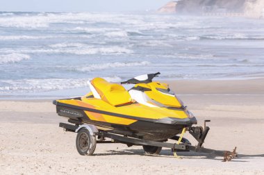 Kumlu bir sahilde bir karavanda jet ski.