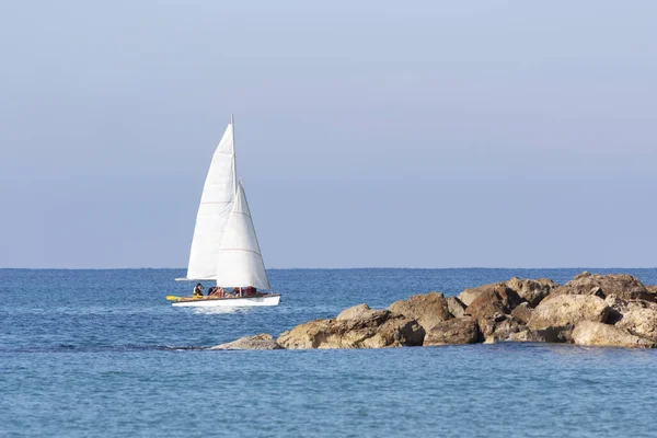 Una barca a vela galleggia accanto a un molo di pietra — Foto Stock
