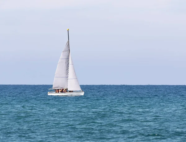 Una barca a vela con un equipaggio in giubbotti di salvataggio galleggia nel mare — Foto Stock