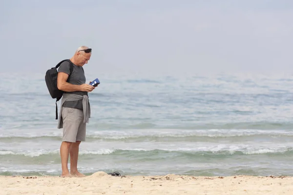 Чоловік з рюкзаком і телефоном на фоні моря — стокове фото
