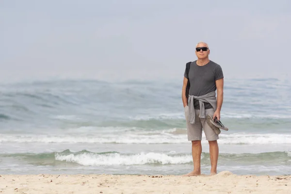 Чоловік стоїть на пляжі в погану погоду — стокове фото
