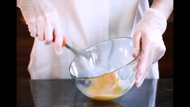 Handschoenenhanden Van Vrouwen Die Eieren Een Transparante Kom Slaan — Stockvideo