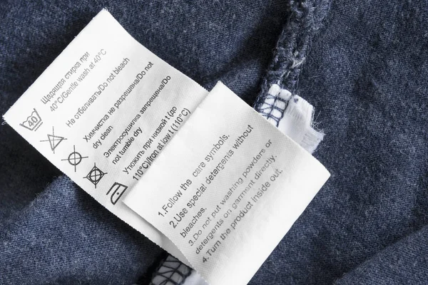 Уход Одеждой Этикетка Русском Английском Языках Синем Текстильном Фоне Крупным — стоковое фото