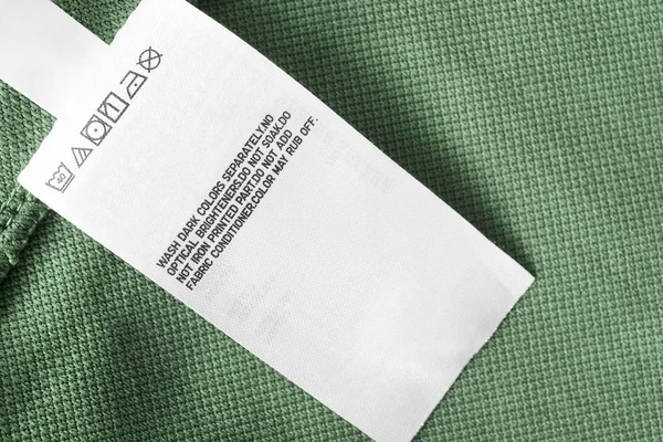 グリーンの布背景クローズ アップの介護服ラベル — ストック写真