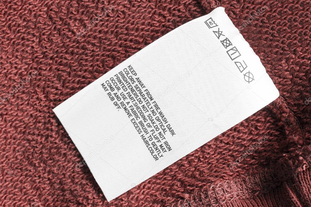 Care clothes label on red textile synthetic background closeup