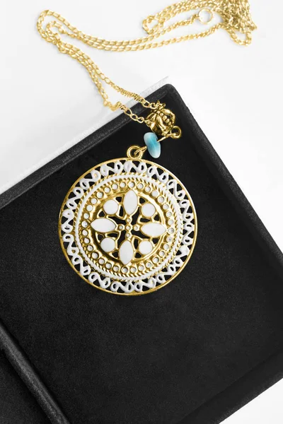 Vintage carved ethnic gold enameled pendant in black jewel box closeup
