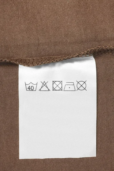 Care clothes label on brown textile background closeup