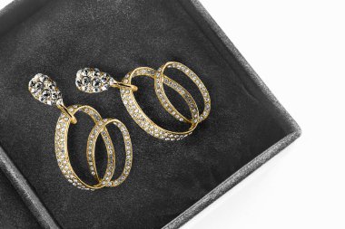 Siyah mücevher kutusunda kristalleri ve elmasları olan lüks altın küpeler.