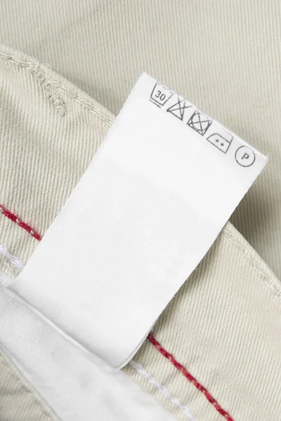 Etykieta Odzieży Pielęgnacyjnej Beżowym Tle Bawełny Zbliżenie — Zdjęcie stockowe