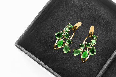 Siyah mücevher kutusunda güzel zümrüt altın küpeler. Yakın plan.