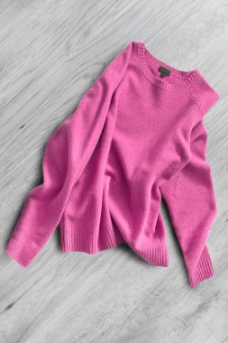 Kırışmış morumsu pembe yün kazak beyaz ahşap arka planda