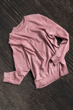 Koyu kahverengi ahşap arka planda buruşmuş pembe kazak.