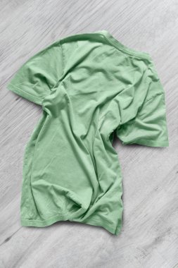 Beyaz ahşap arka planda buruşuk yeşil tişört