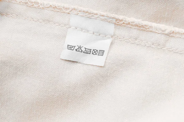 Etiqueta Ropa Cuidado Sobre Fondo Textil Beige —  Fotos de Stock