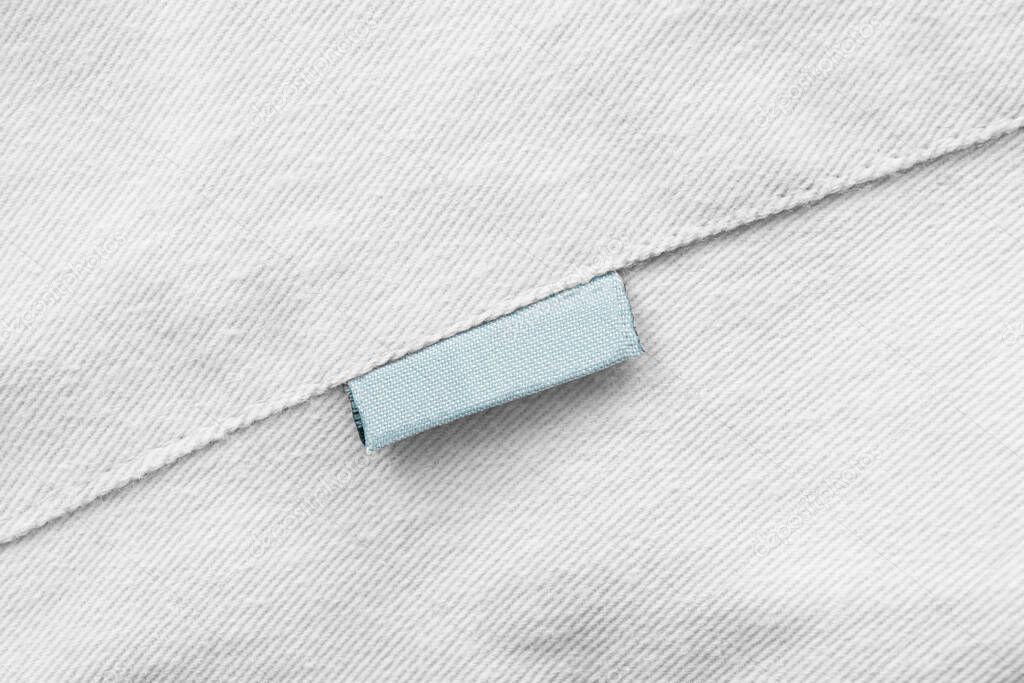 Blank blue clothes label on white textile background