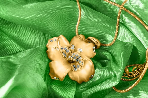 古式金项链 花形吊坠在绿色缎子的特写上 — 图库照片