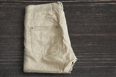 Koyu ahşap arka planda katlanmış bej pantolon